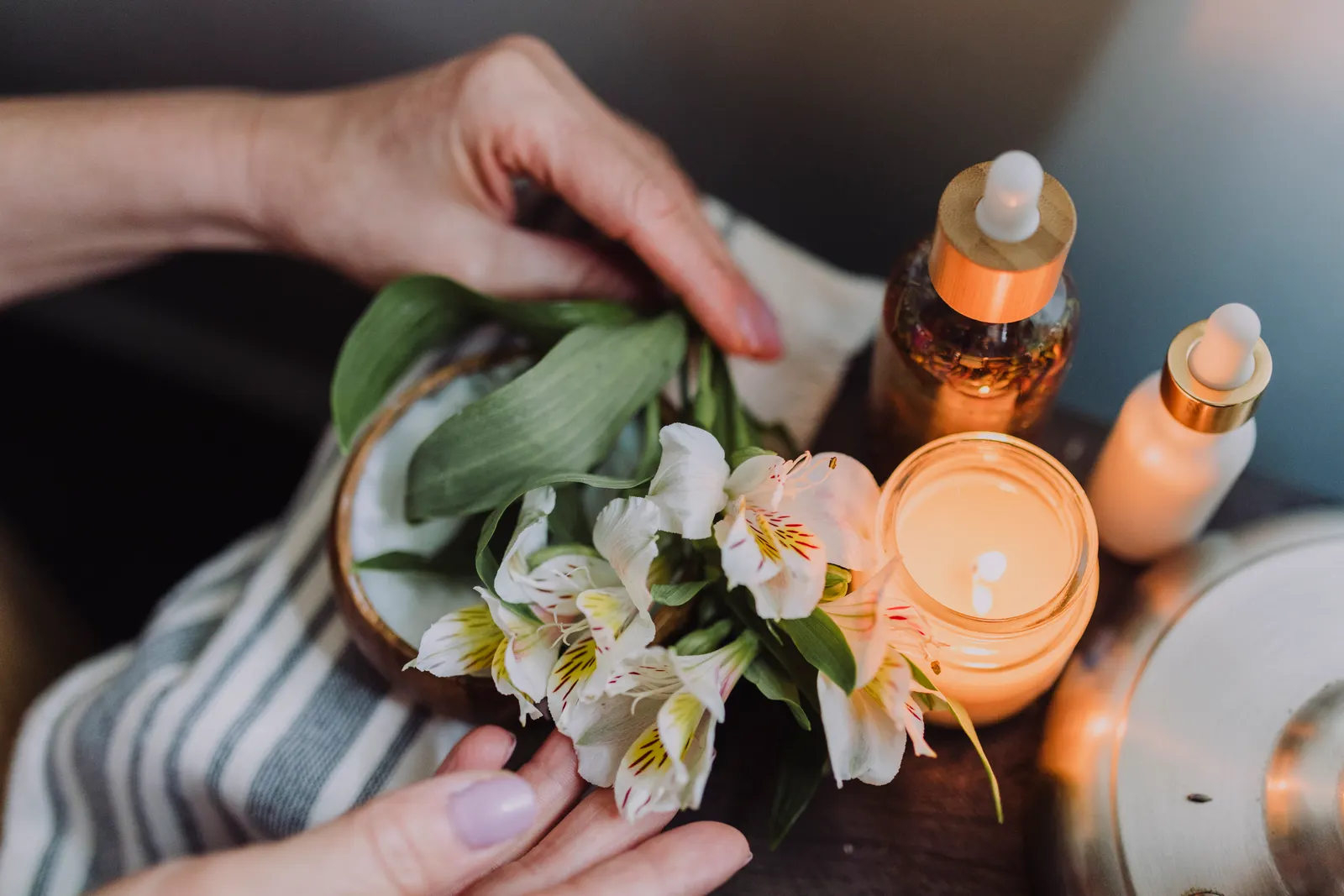 Candlelit spa setting with hands arranging delicate white flowers