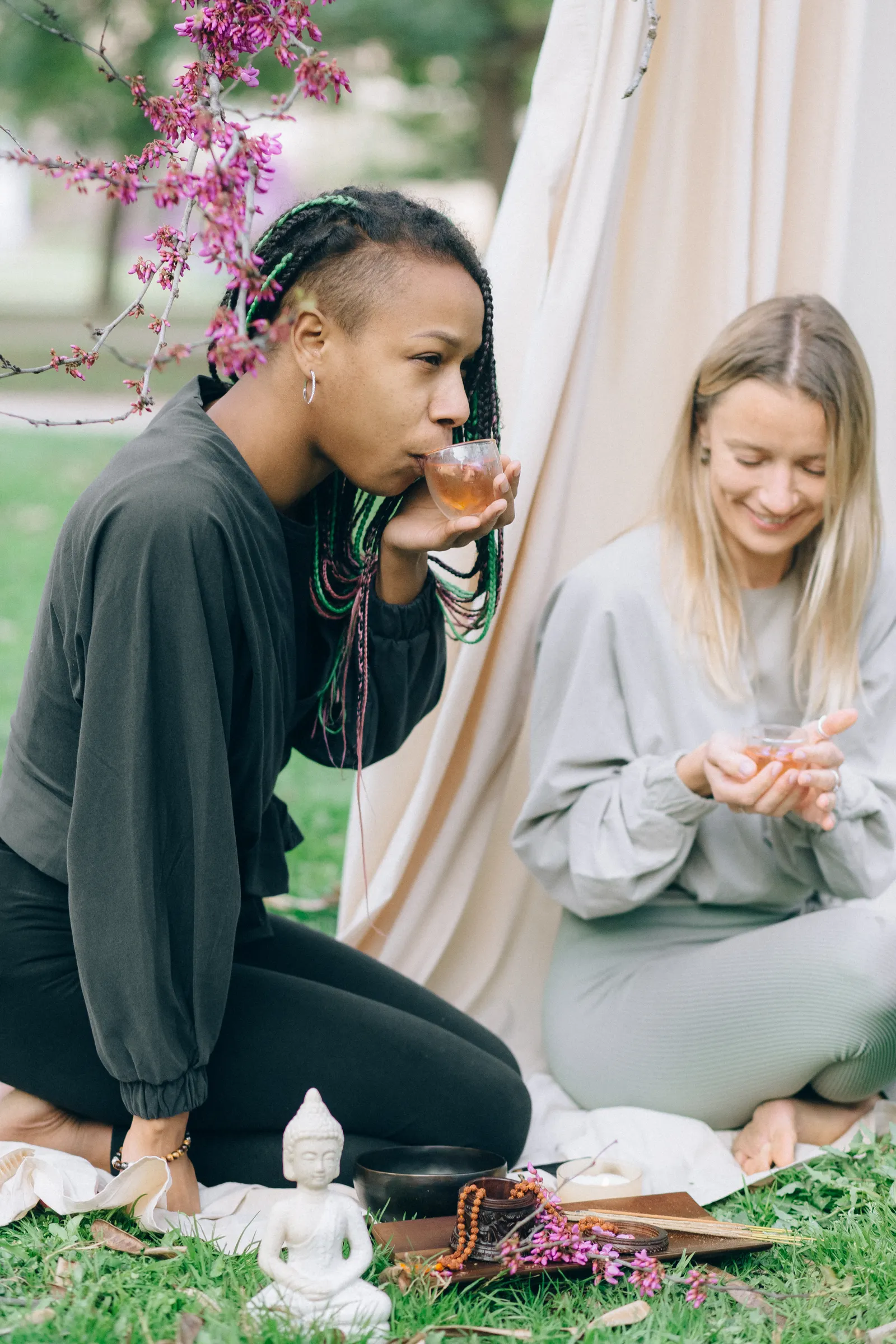 Two women sharing a mindful moment with tea in a tranquil outdoor setting